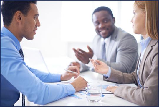 Three professionals standing in an office speaking to each other